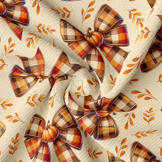 a fabric with a repeating pattern of plaid bows and autumn leaves in shades of orange and brown.