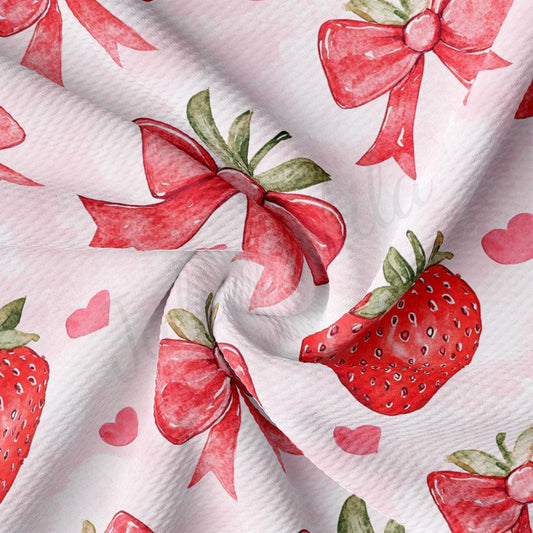 a close-up view of a fabric with a repeating pattern of red bows and strawberries.