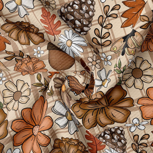 The image is a close-up of a fabric with a repeating pattern of various flowers and leaves in shades of brown, white, and orange.