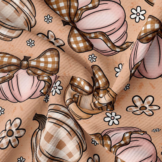 The image is a close-up of a fabric with a repeating pattern of pink pumpkins and white flowers. The pumpkins are adorned with bows, and the flowers are scattered throughout the fabric, creating a visually appealing and textured design.