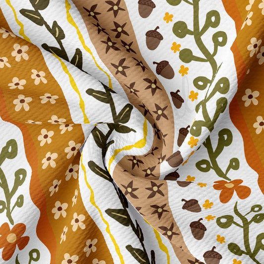 The image is a close-up of a fabric with a repeating pattern of flowers, leaves, and acorns in various colors such as orange, green, and brown.