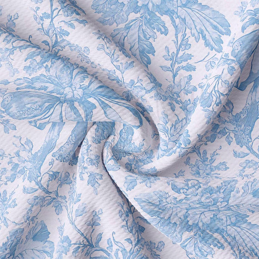 a close-up view of a fabric with a floral pattern in shades of blue and white. The fabric appears to be crumpled and wrinkled, giving it a textured and soft appearance.