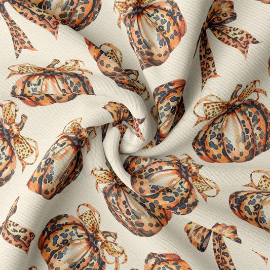 a close-up view of a fabric with a repeating pattern of leopard print pumpkins and bows.