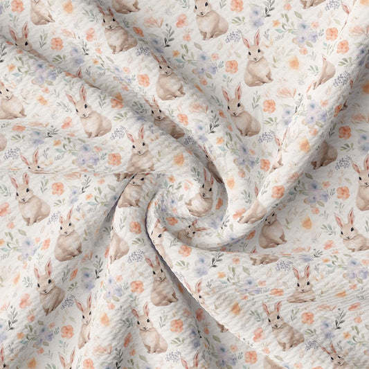 a close up of a white fabric with rabbits and flowers on it