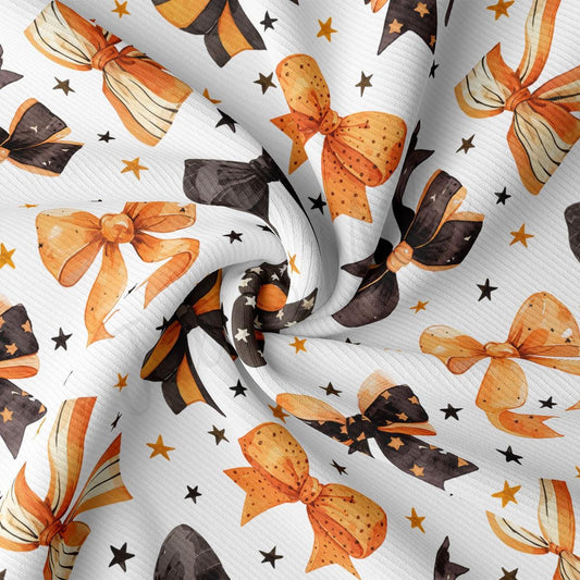 a close-up view of a fabric with a repeating pattern of orange and black bows, along with scattered stars.