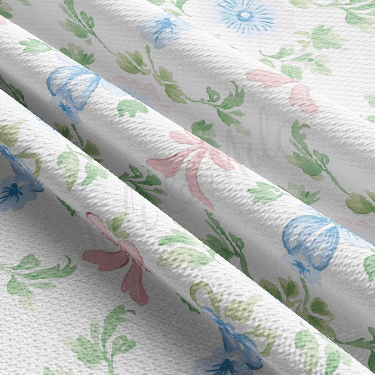 a close-up view of a fabric with a floral pattern, including blue and green flowers and leaves. The fabric appears to be white and has a textured appearance.