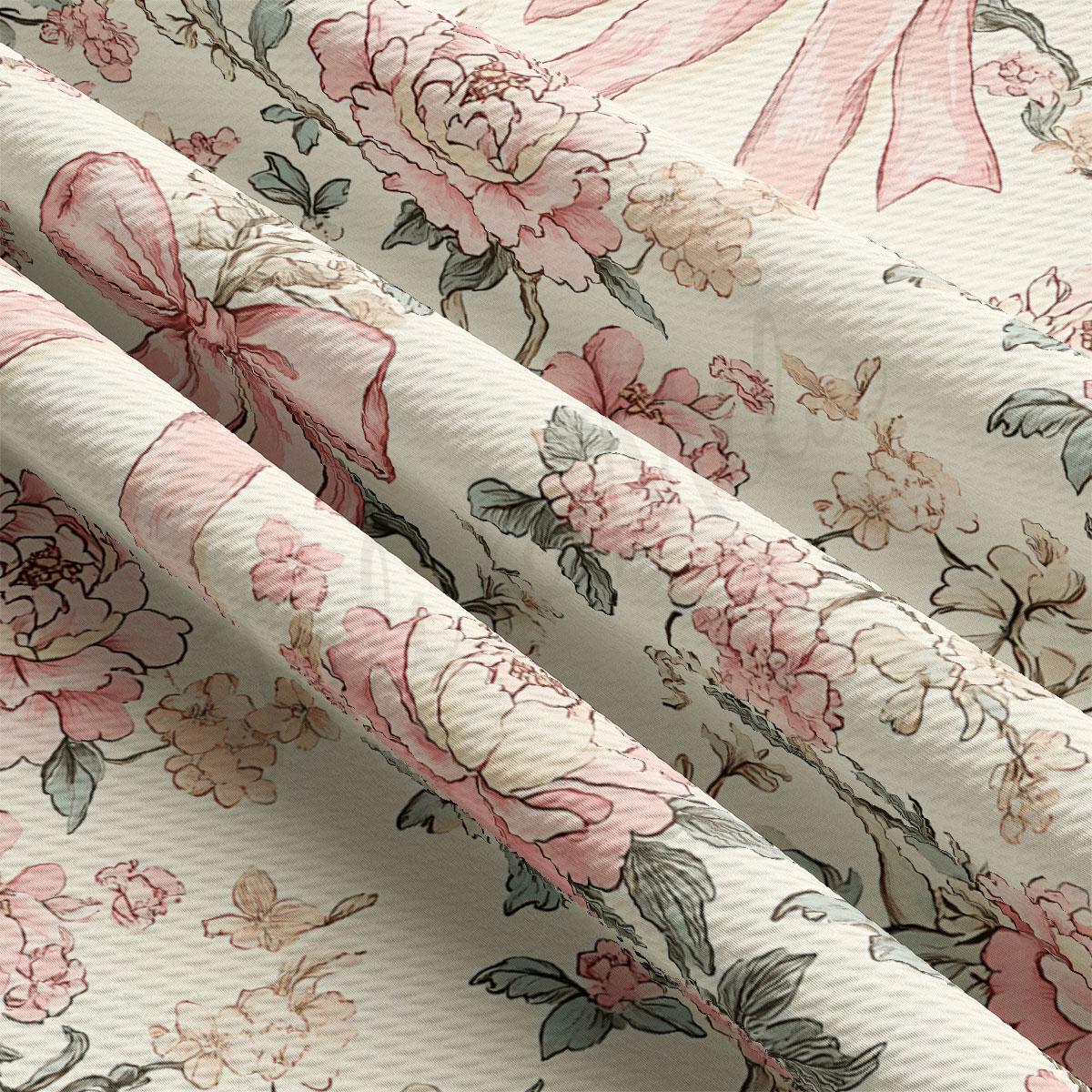 a close-up view of a fabric with a floral pattern, including pink and white flowers and leaves. The fabric appears to be folded or rolled, revealing the intricate design and texture of the floral pattern.
