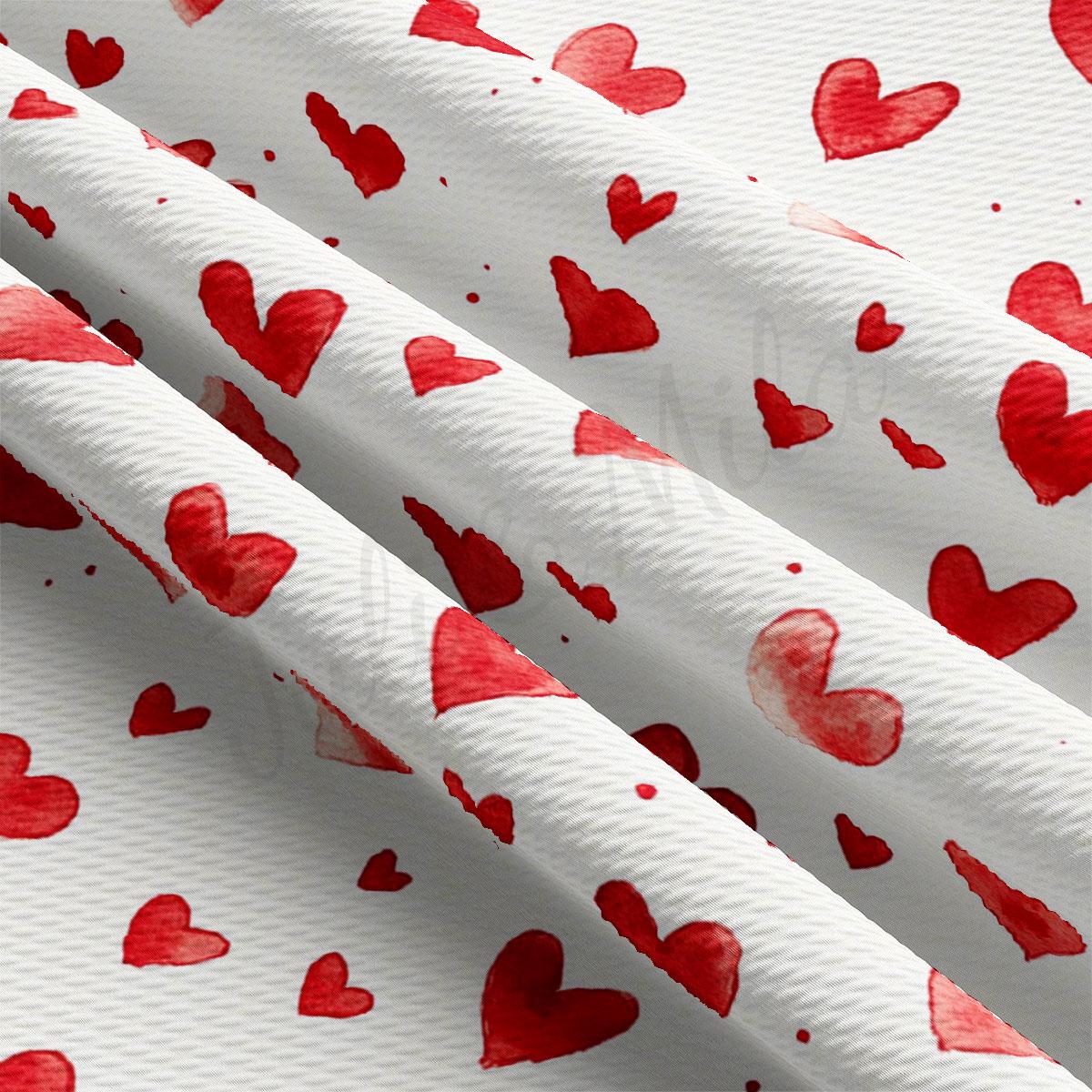 a close-up view of a fabric with a repeating pattern of red hearts on a white background.