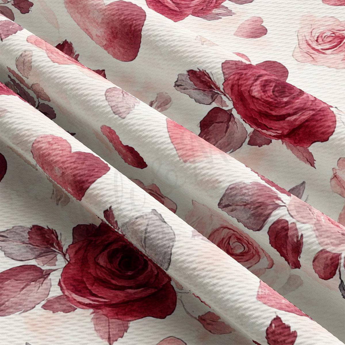 a close-up view of a fabric with a floral pattern of red roses and pink hearts. The fabric appears to be made of a soft, white material, and the pattern is quite intricate and detailed.