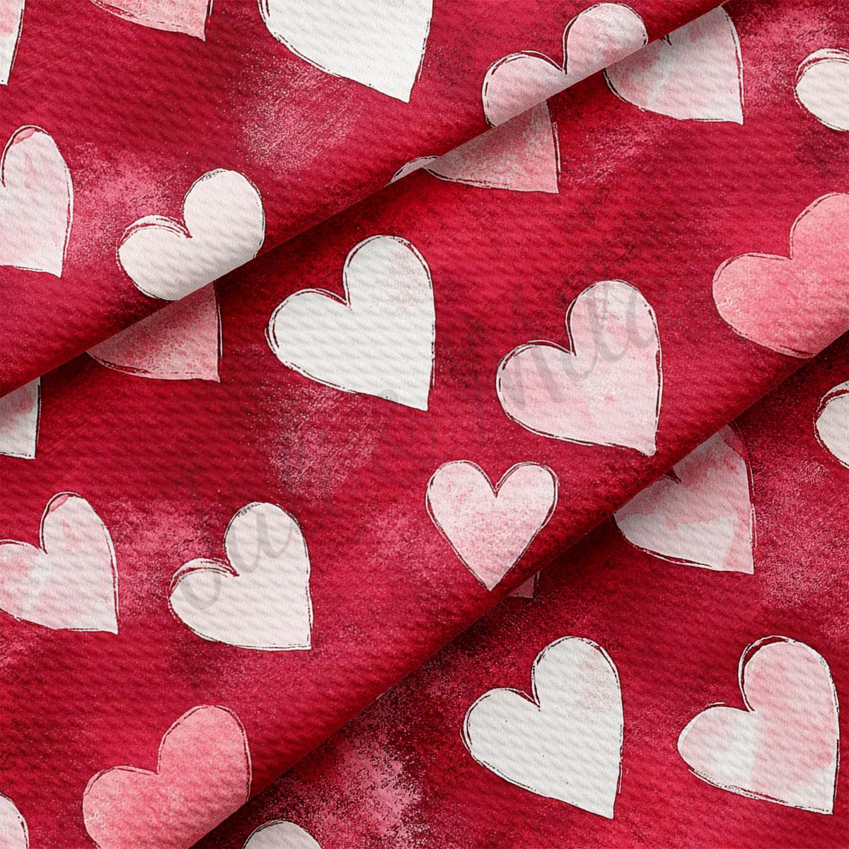 a close-up view of a red fabric with white hearts printed on it. The hearts are arranged in a repeating pattern, creating a visually striking and textured design.