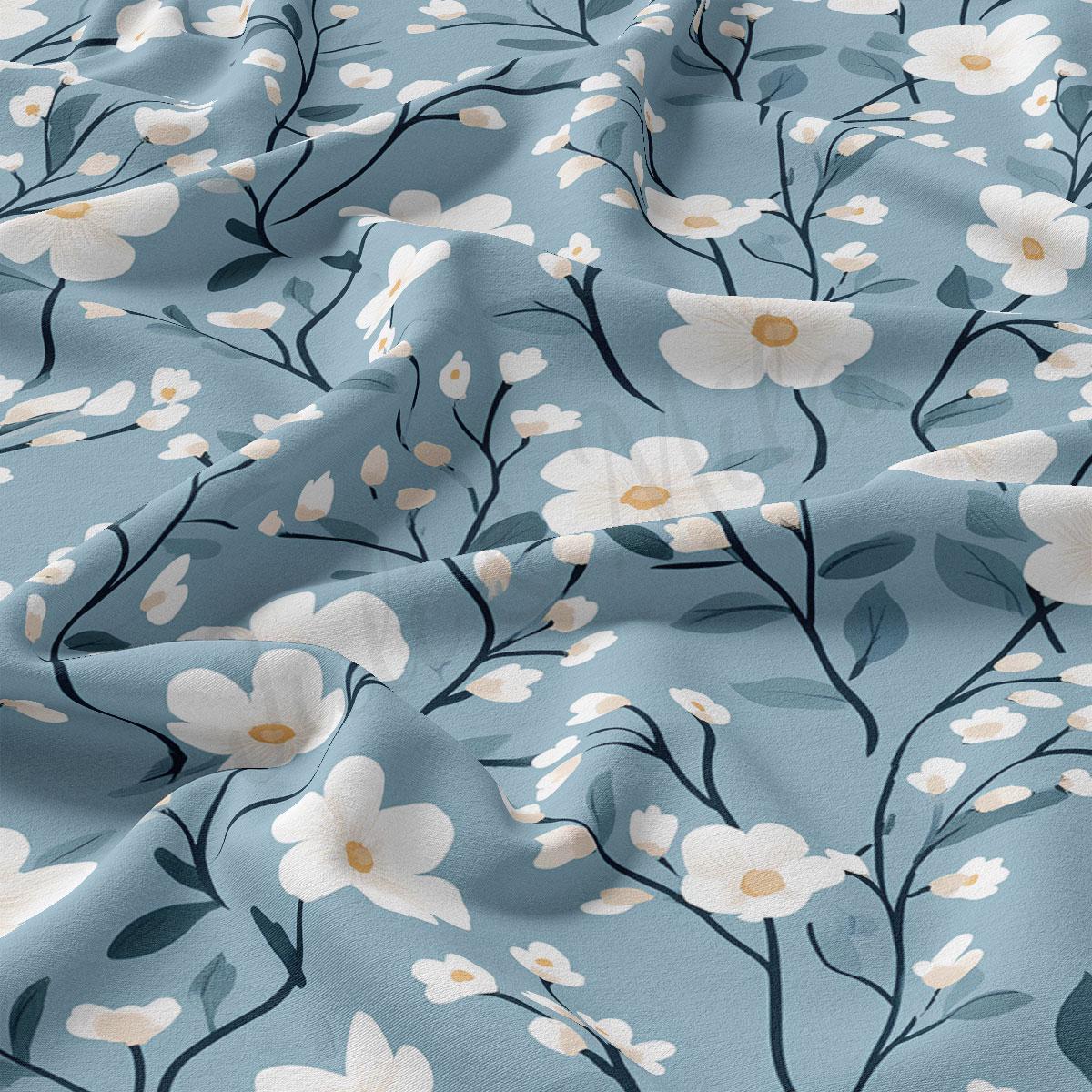 a close-up view of a fabric with a repeating floral pattern of white flowers and green leaves against a light blue background.