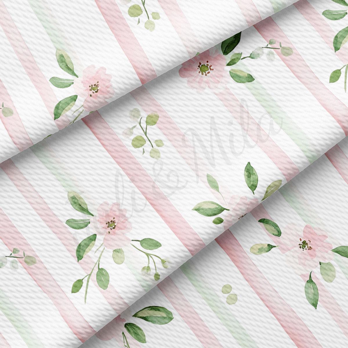 a close-up view of a fabric with a floral pattern. The fabric has pink and green stripes, and there are green leaves and pink flowers printed on it.