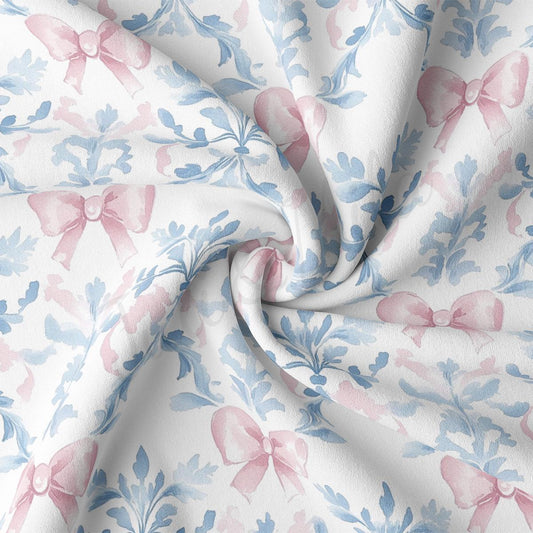 a close-up view of a fabric with a floral pattern of pink bows and blue leaves. The fabric appears to be made of a soft, white material and is crumpled, giving it a textured and cozy appearance.