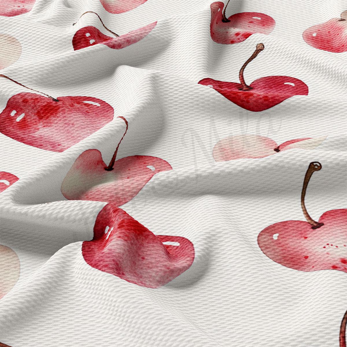a close-up view of a white fabric with a repeating pattern of red cherries.
