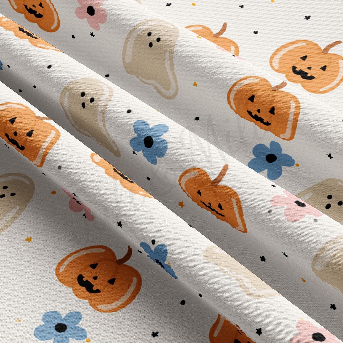 a close-up view of a fabric with a repeating pattern of Halloween-themed pumpkins and ghost shapes.