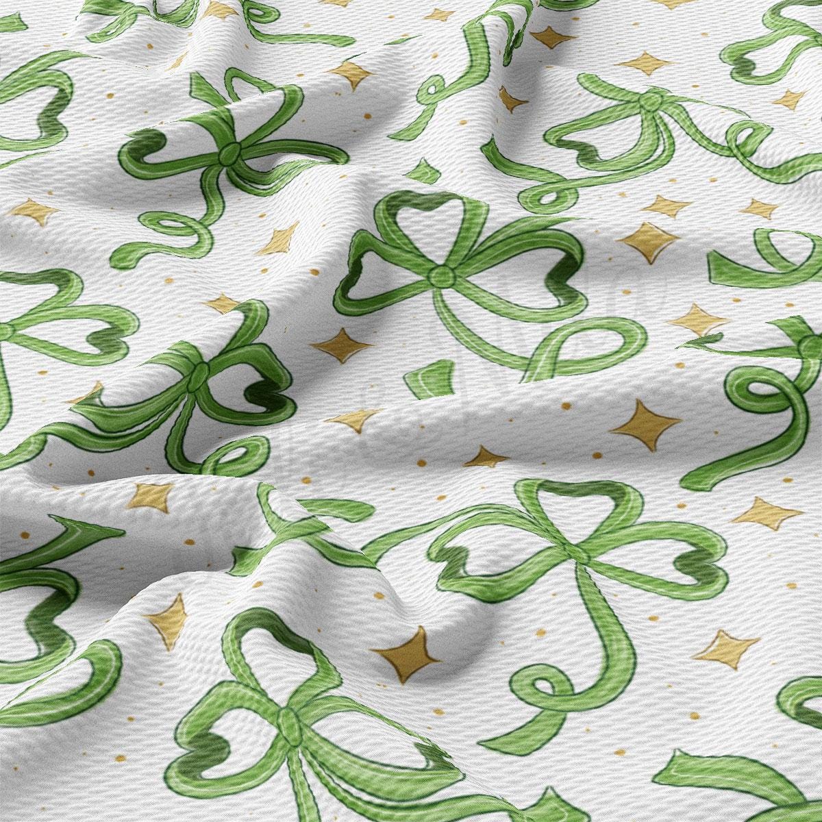 a close up of a white fabric with green and gold designs