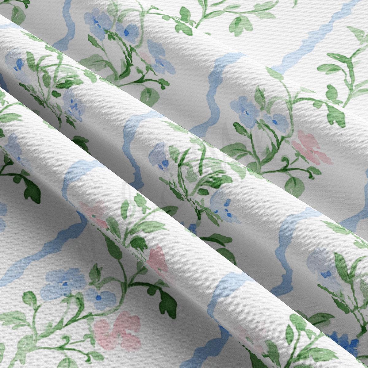 a close-up view of a fabric with a floral pattern, including blue and green flowers and leaves. The fabric appears to be white and has a textured appearance.