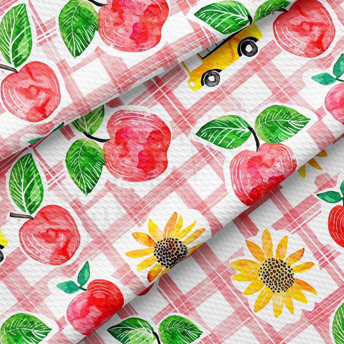 a red and white checkered table cloth with apples and sunflowers on it