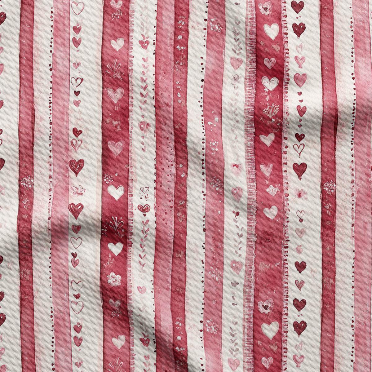 a close-up view of a fabric with a repeating pattern of pink and white stripes. The pattern consists of vertical stripes with heart shapes and floral designs scattered throughout, creating a visually appealing and textured appearance.