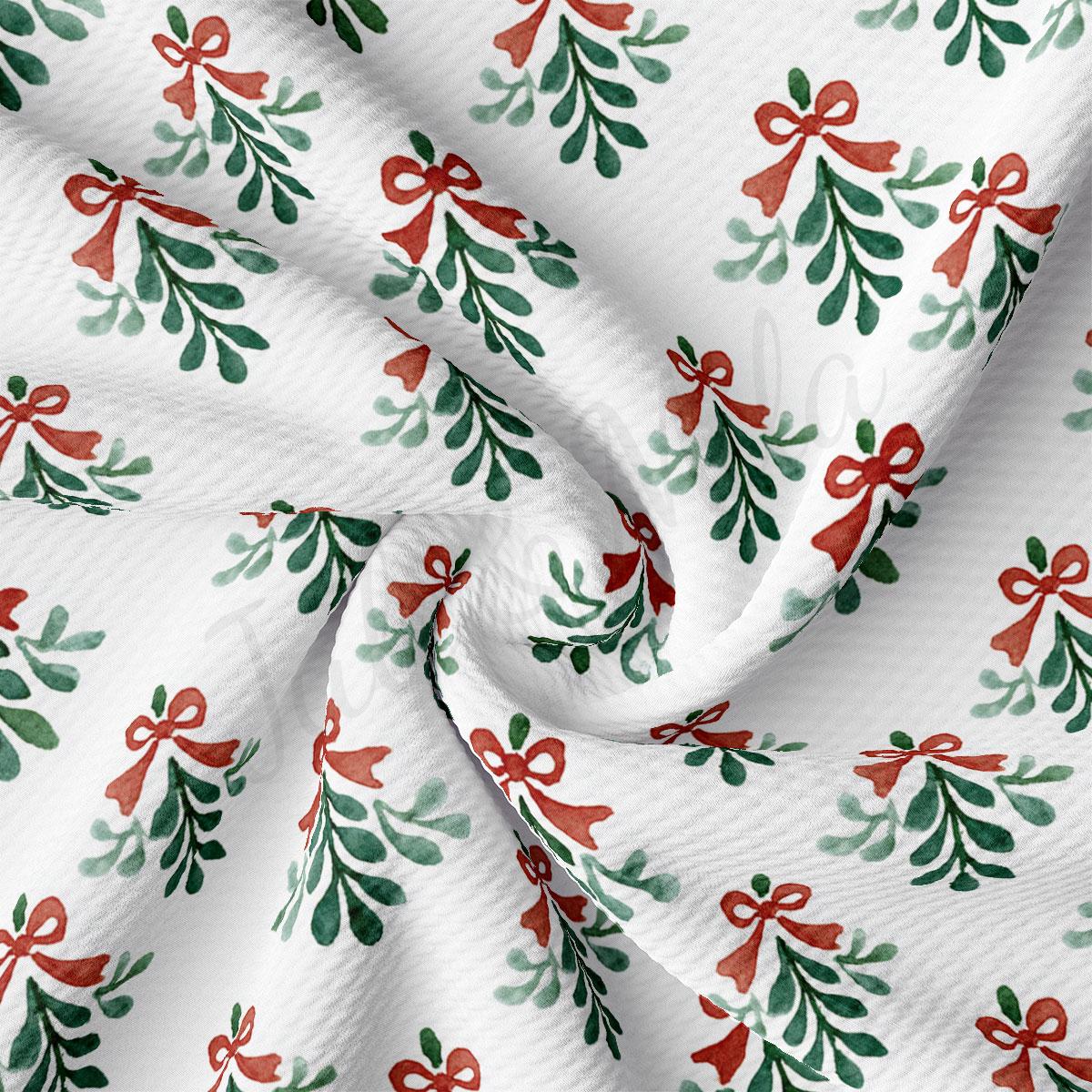 a close-up view of a fabric with a repeating pattern of green and red Christmas-themed designs, including mistletoe and red bows.