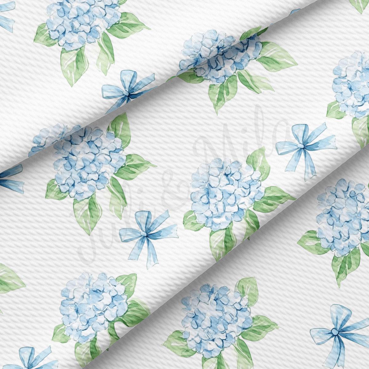 a repeating pattern of blue hydrangea flowers with green leaves and bows on a white background.