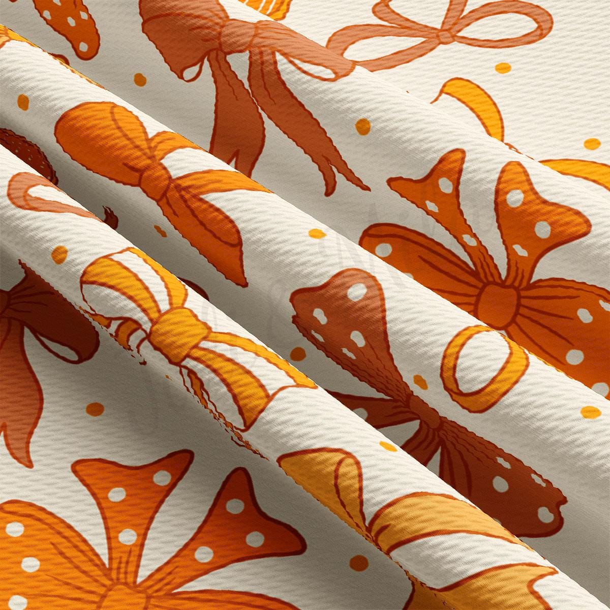 a close-up view of a fabric with a repeating pattern of orange and white bows and flowers. The fabric appears to be folded or rolled, revealing the intricate design and texture of the pattern.