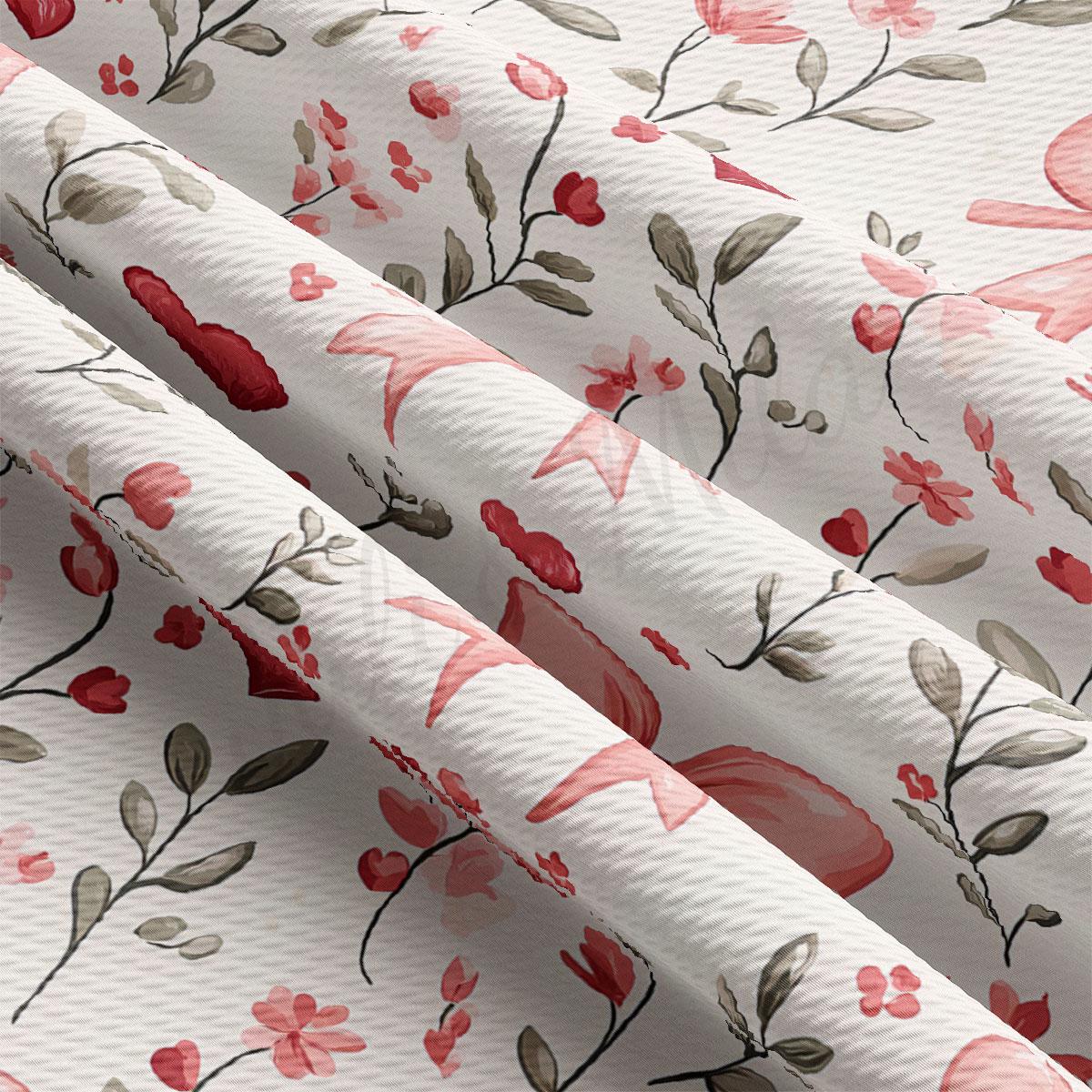 a close-up view of a fabric with a floral pattern. The fabric has a white background with pink and red flowers and leaves, creating a visually appealing and vibrant design.