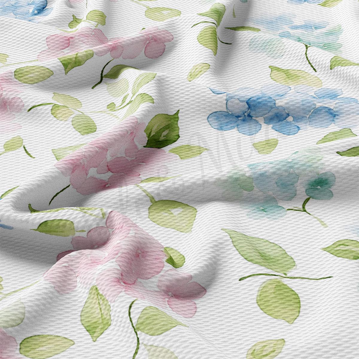 a close-up view of a fabric with a floral pattern, including pink flowers and green leaves. The fabric appears to be white, and the pattern is intricate and detailed.