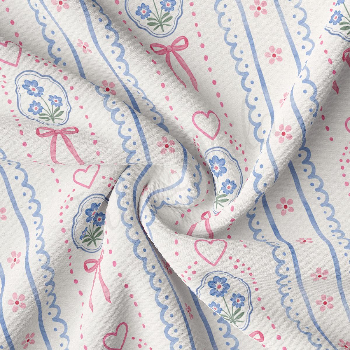 The image is a close-up of a fabric with a floral pattern, featuring blue and pink flowers, hearts, and bows.