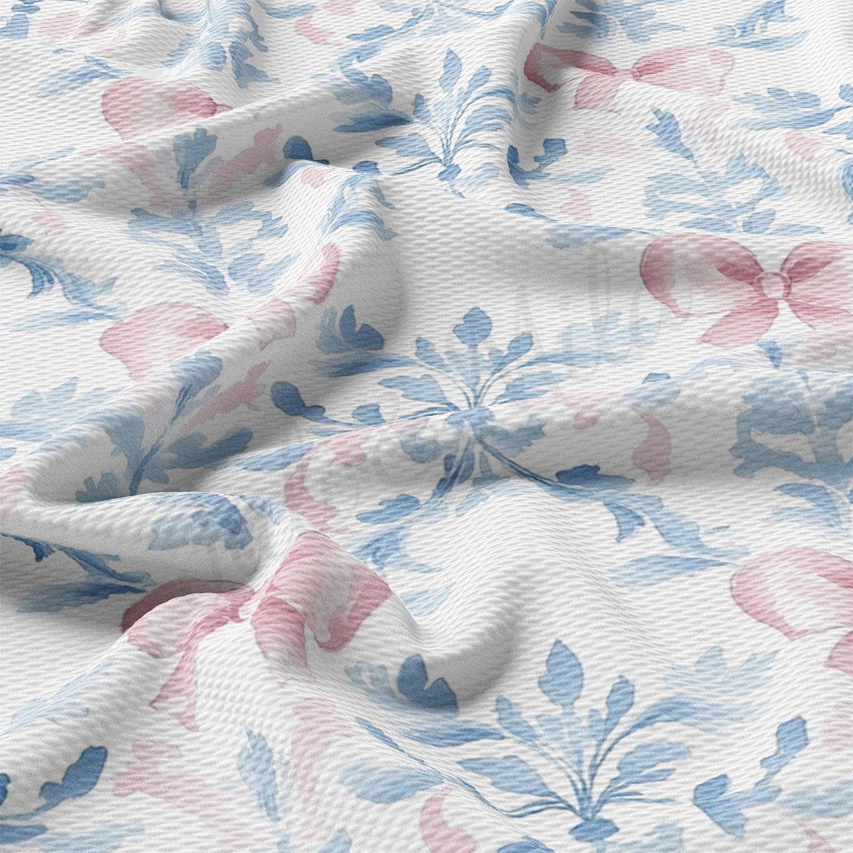 a close-up view of a fabric with a floral pattern in shades of blue and pink. The fabric appears to be crumpled and wrinkled, giving it a textured and soft appearance.