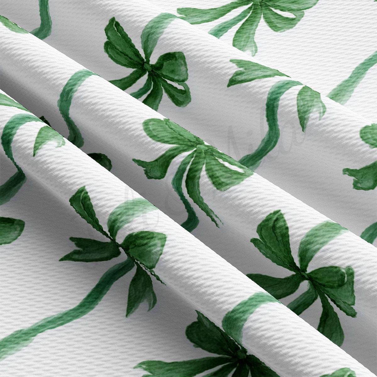 a close-up view of a fabric with a repeating pattern of green bows on a white background.