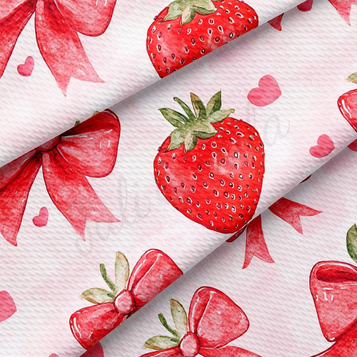 a close-up view of a fabric with a repeating pattern of red strawberries and red bows.