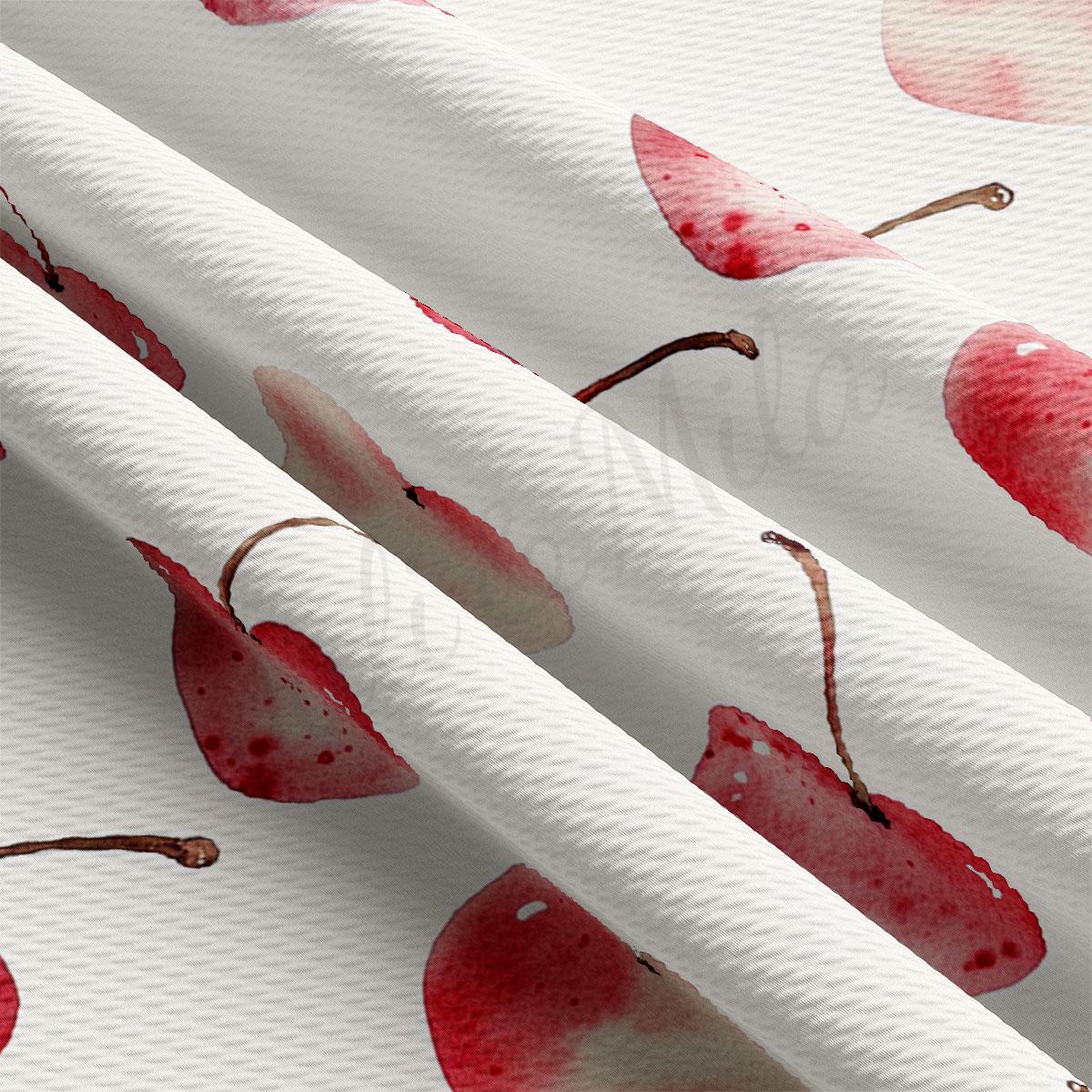 a close-up view of a fabric with a repeating pattern of red cherries.