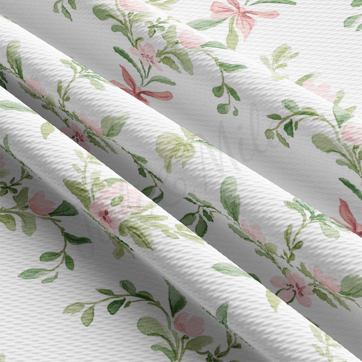 a close-up view of a fabric with a floral pattern, including pink and green flowers and leaves. The fabric appears to be white and has a textured appearance.