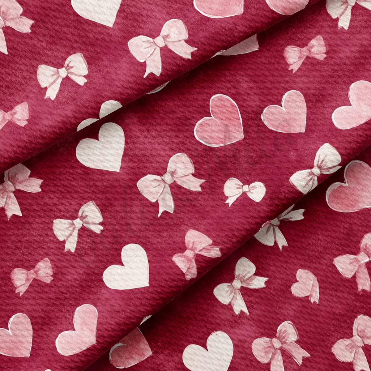a close-up view of a fabric with a repeating pattern of white hearts and bows on a maroon background.