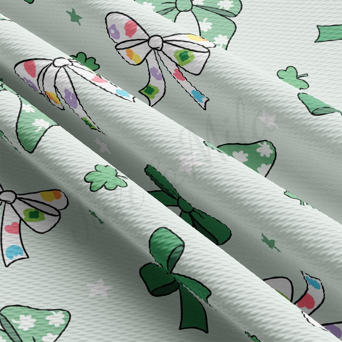 a close up of a white fabric with bows and shamrocks on it
