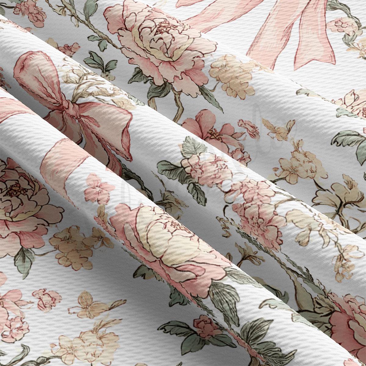 a close-up view of a fabric with a floral pattern, including pink and white flowers and leaves. The fabric appears to be folded or rolled, revealing the intricate design and texture of the floral pattern.