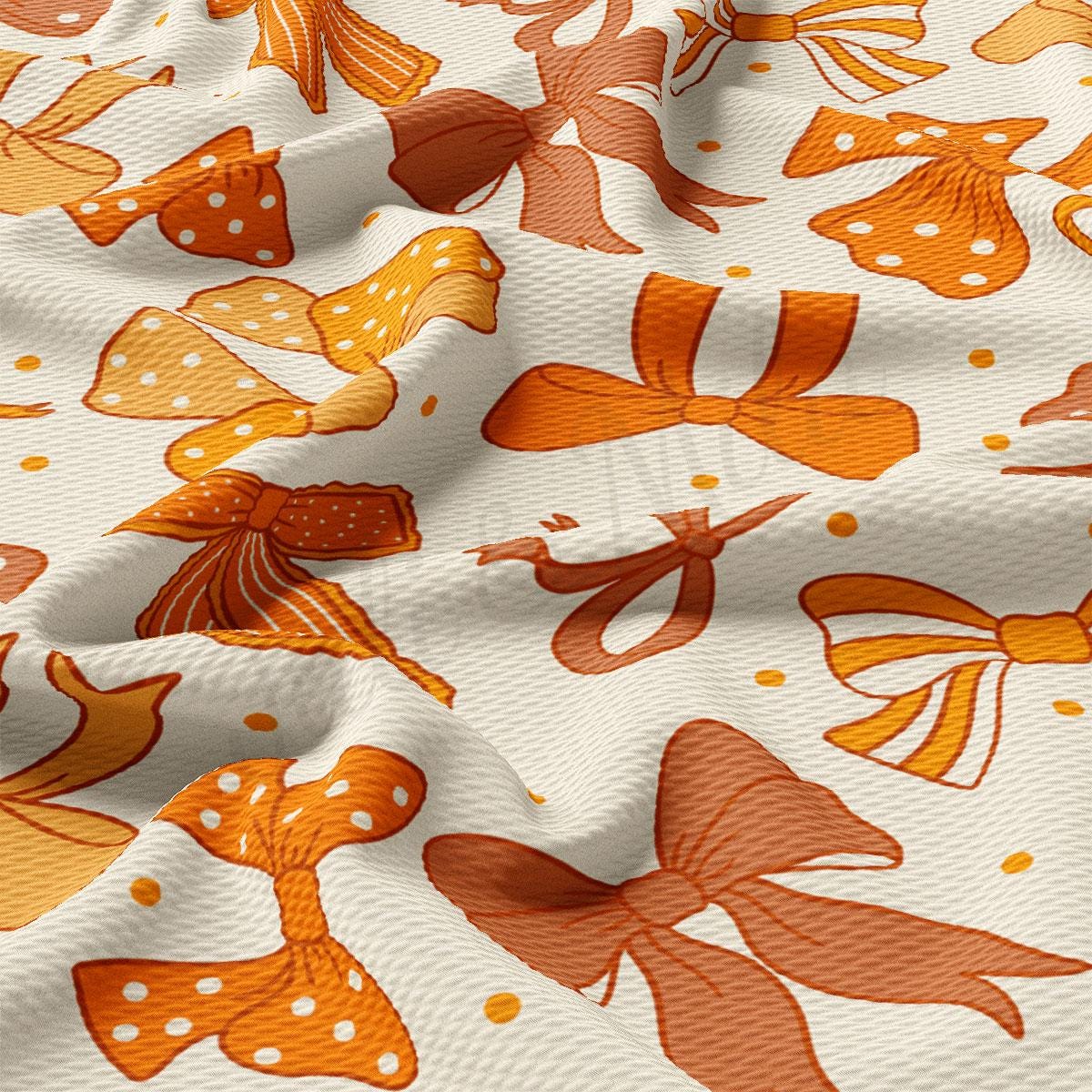 a close-up view of a fabric with a repeating pattern of orange and white bows. The bows are arranged in various sizes and orientations, creating a visually interesting and textured design.