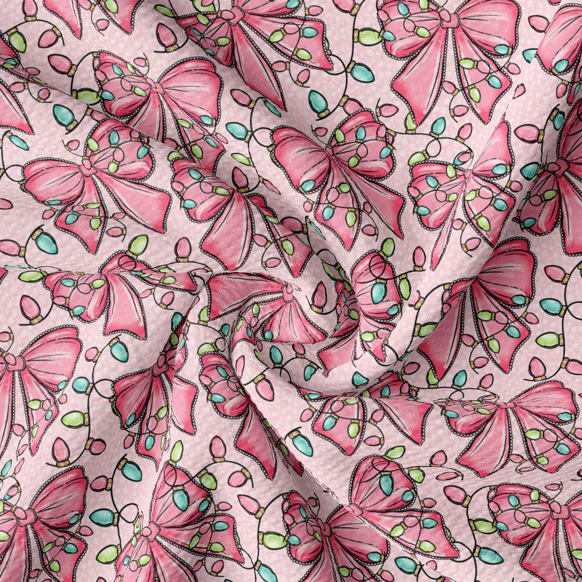 a close-up view of a fabric with a repeating pattern of pink bows and green leaves. The bows are arranged in a diagonal pattern, creating a sense of movement and dynamism across the fabric. The green leaves add a touch of nature and freshness to the overall design. The fabric appears to be made of a soft, plush material, suitable for clothing or home decor.