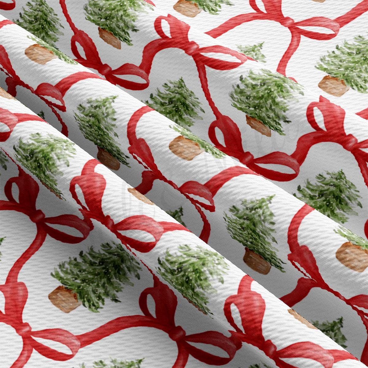 a repeating pattern of Christmas trees and red bows on a fabric surface.