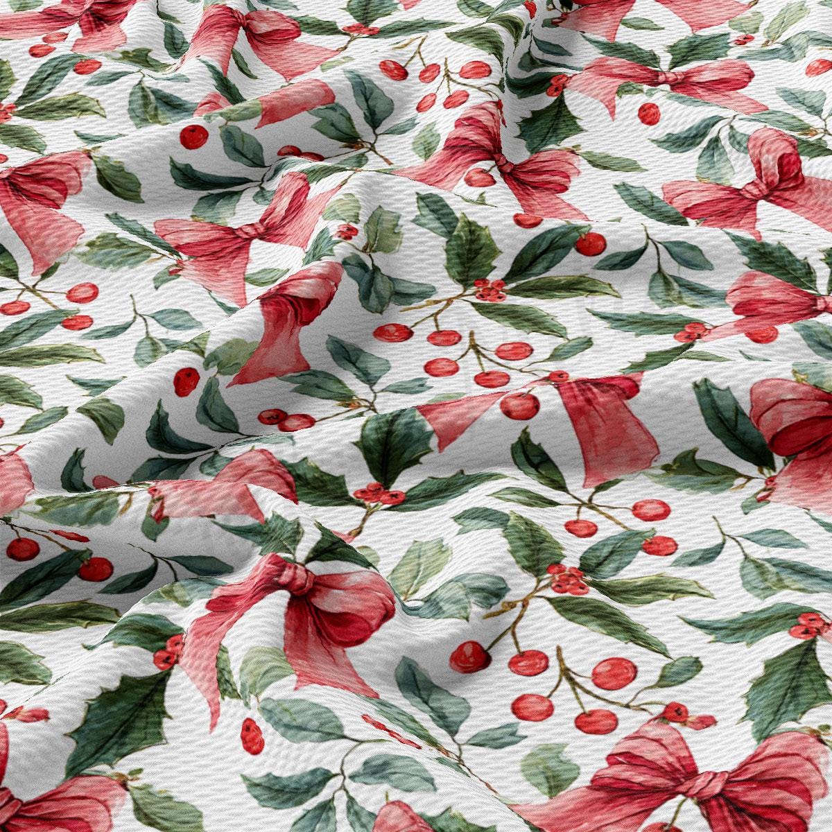 a close-up view of a fabric with a floral pattern of red bows, green leaves, and red berries. The fabric appears to be made of a soft, white material, and the pattern is intricate and detailed.