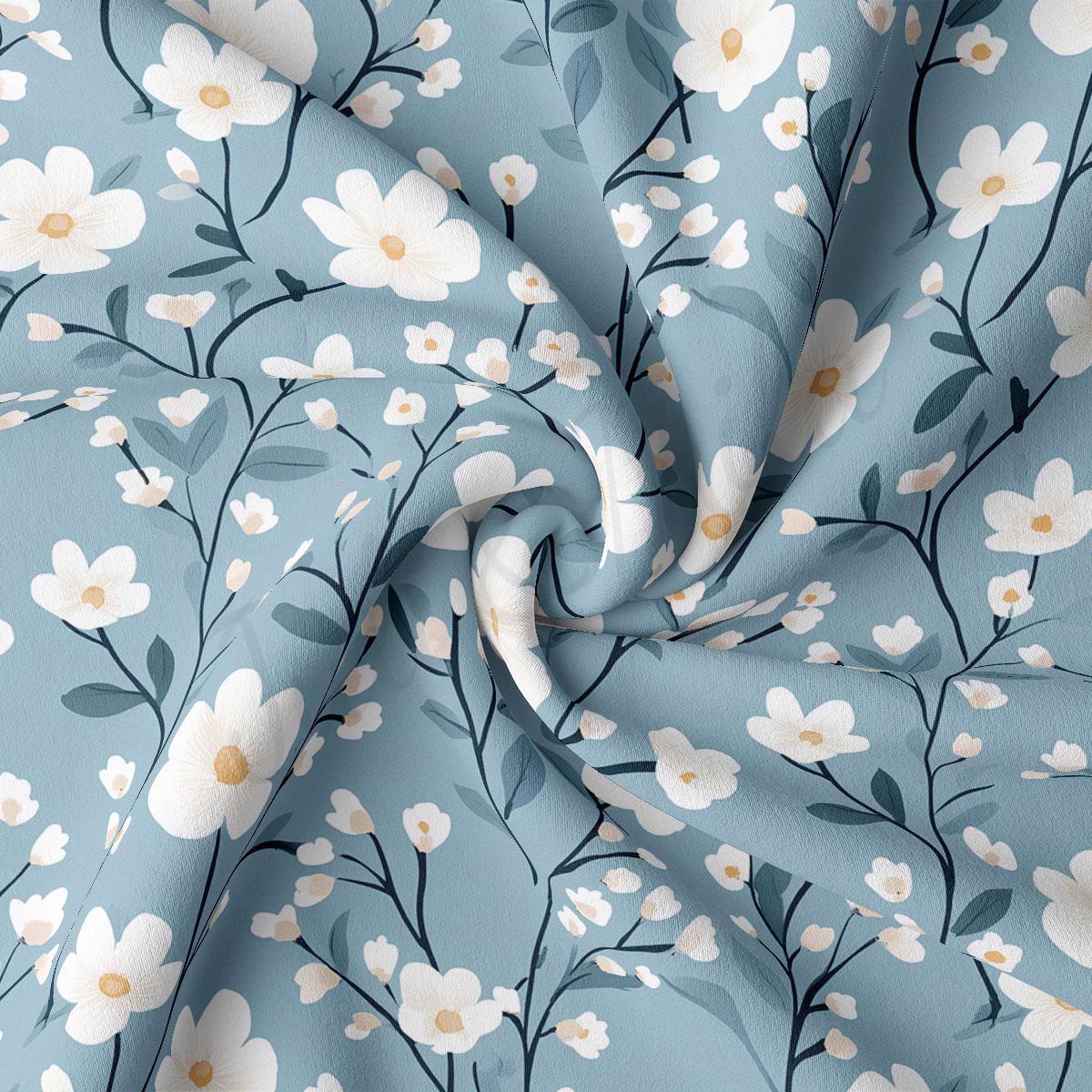 a close-up view of a fabric with a floral pattern. The fabric has a blue background with white flowers and green leaves, creating a visually appealing and harmonious design.