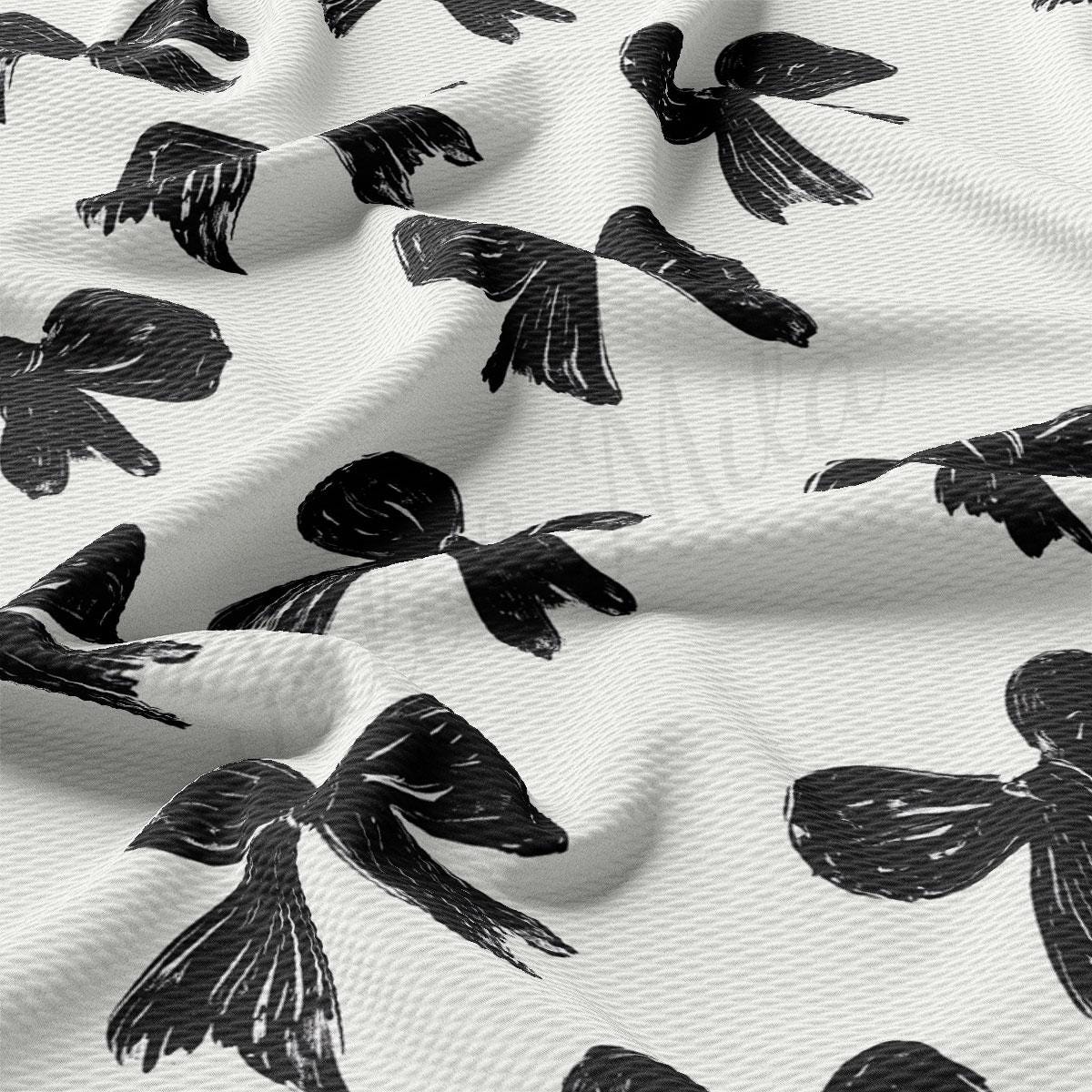 a close-up view of a fabric with a repeating pattern of black silhouettes of birds or other winged creatures. The pattern is predominantly black, with some white accents visible. The birds appear to be in various poses, creating a dynamic and visually interesting design.