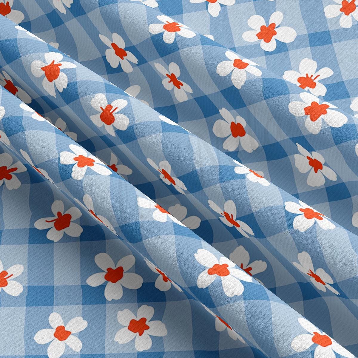 a blue and white checkered fabric with red and white flowers